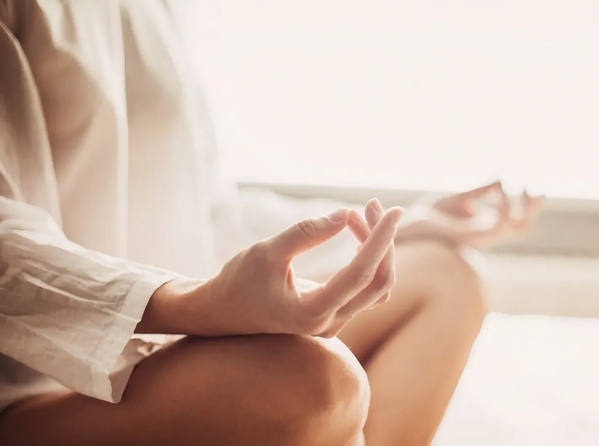 A person sitting on the ground with their hands in yoga pose.